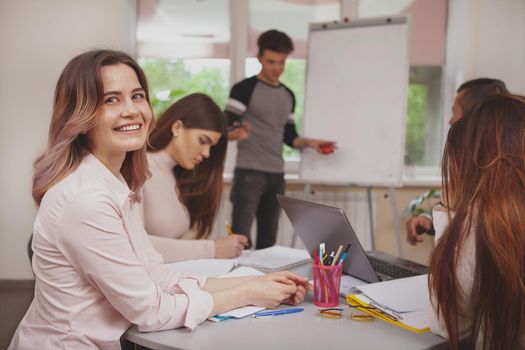 Education, ideas concept. Lovely happy young female student smiling to the camera during presentation at class, copy space. Attractive young woman enjoying studying with her friends