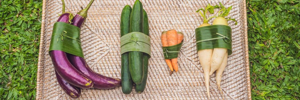 BANNER, LONG FORMAT Eco-friendly product packaging concept. Vegetables wrapped in a banana leaf, as an alternative to a plastic bag. Zero waste concept. Alternative packaging.