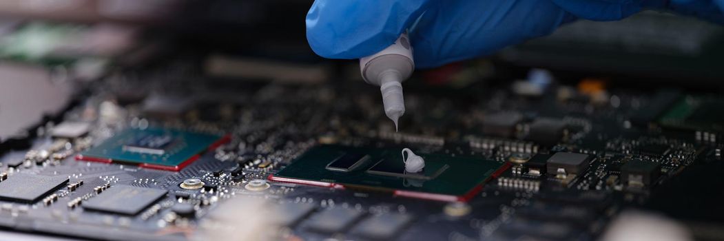 Thermal paste for the processor, computer repair, hands close-up. Workshop for servicing electronic devices, part of a laptop