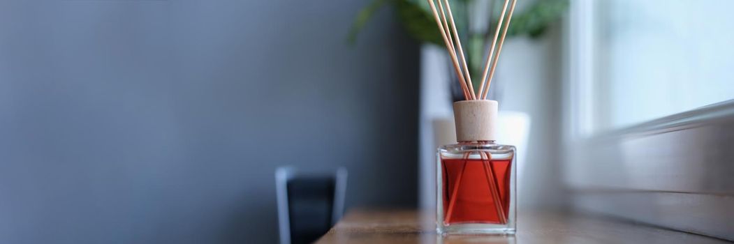 Diffuser with wooden sticks on the windowsill. Aromatherapy for an apartment, pleasant scent of perfume. Aroma bottle with essential oil