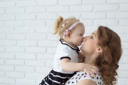 Mother helps her deaf baby daughter putting hearing aid in little girl's ear indoors - cochlear implant and innovative medical technologies