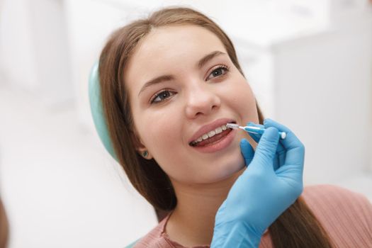 Close up of a beautiful woman getting dental treatment by dentist, using interdental toothbrush