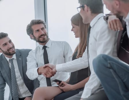 young business people shaking hands while sitting in the office lobby . business concept