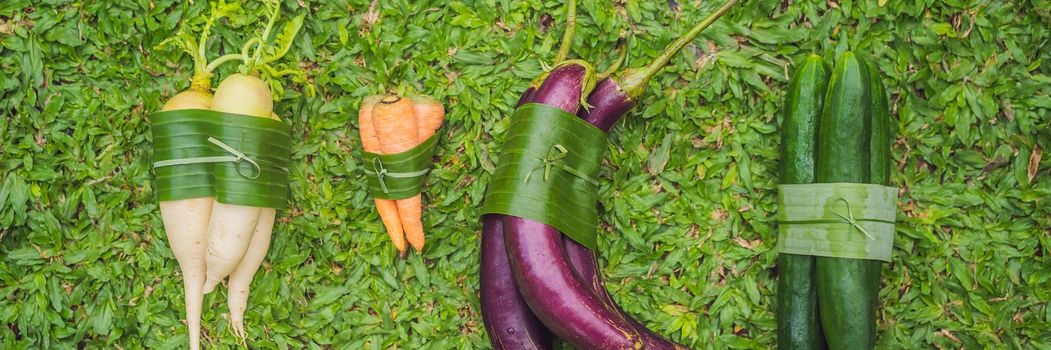 BANNER, LONG FORMAT Eco-friendly product packaging concept. Vegetables wrapped in a banana leaf, as an alternative to a plastic bag. Zero waste concept. Alternative packaging.