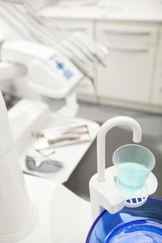 Vertical close up of glass of mouth wash on dental sink