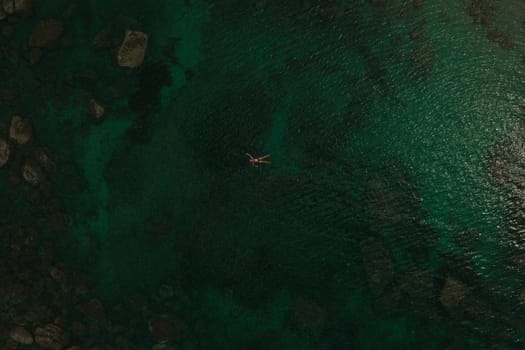 Aerial top nature view above green turquoise Adriatic sea in Albania. Beautiful young woman swimming alone in middle ocean water. girl in swimsuit bikini lying. wide panoramic view marine. summer