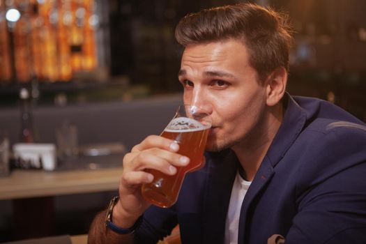 Close up of a handsome elegant man drinking delicious beer at the pub