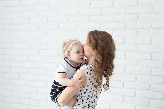 Mother helps her deaf baby daughter putting hearing aid in little girl's ear indoors - cochlear implant and innovative medical technologies