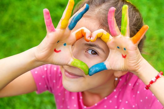 Hands of a child with a drawn emoticon. Selective focus.