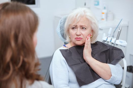 Elderly woman suffering from toothache, visiting dentist