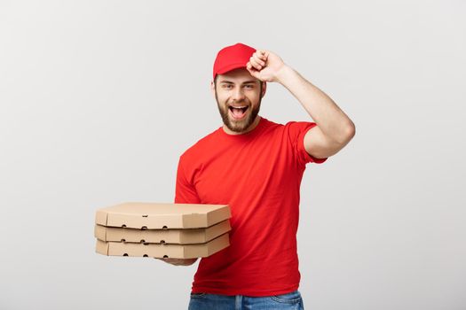 Delivery Concept: Handsome pizza delivery man courier in red uniform with cap holding pizza boxes. Isolated on white