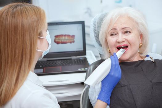 Elderly woman getting dental 3d scanning by her dentist