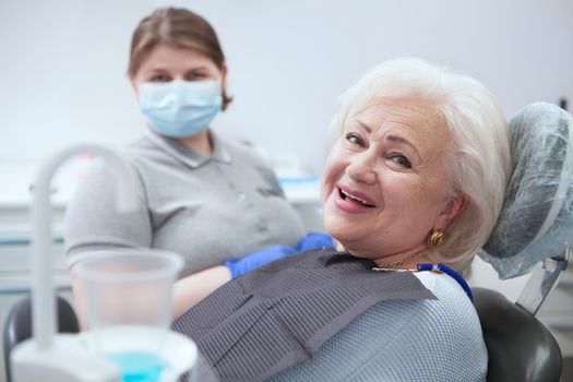 Happy elderly lady smiling to the camera, after dental checkup at the clinic