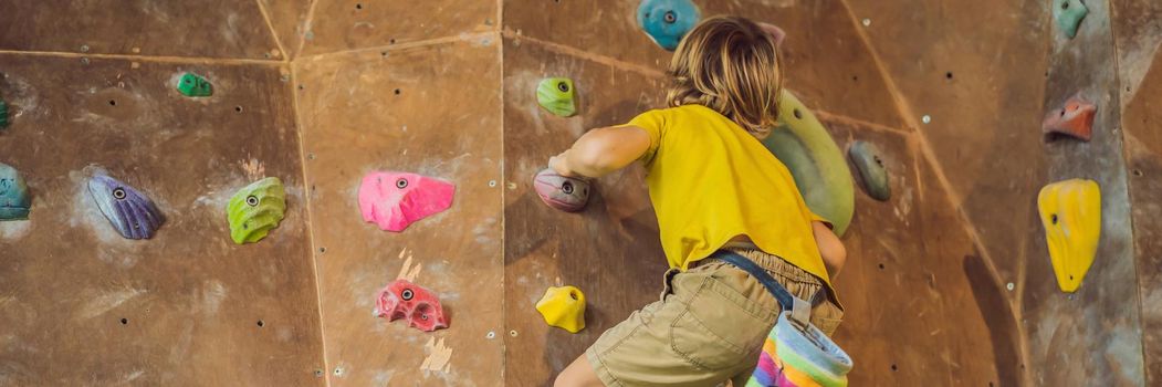 little boy climbing a rock wall in special boots. indoor. BANNER, LONG FORMAT