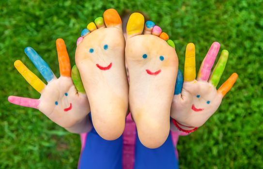 Feet of a child on the grass with a painted smile. Selection focus. Kid.