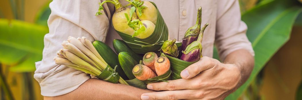 BANNER, LONG FORMAT Eco-friendly product packaging concept. Vegetables wrapped in a banana leaf, as an alternative to a plastic bag. Zero waste concept. Alternative packaging.