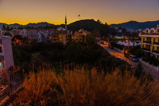 MARMARIS, MUGLA, TURKEY: Evening landscape with a view of hotels, residential buildings and a mosque in Marmaris at sunset.