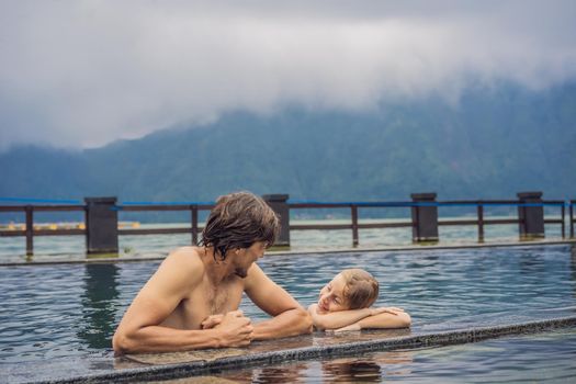 Dad and son travelers in Hot Springs in Bali on the background of lake. Traveling with children concept.