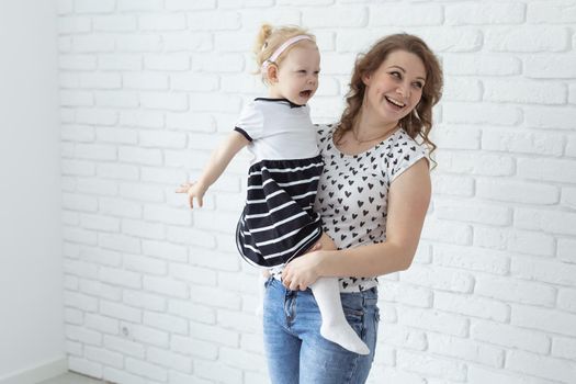 Mother helps her deaf baby daughter putting hearing aid in little girl's ear indoors - cochlear implant and innovative medical technologies