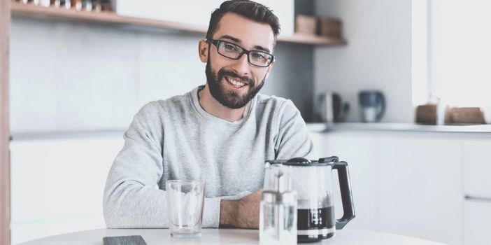 close up. attractive man sitting at the kitchen table in the morning