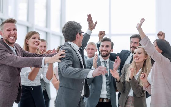 group of cheerful company employees congratulating their colleague. success concept