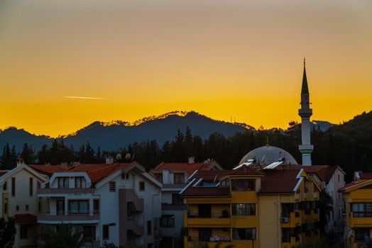 MARMARIS, MUGLA, TURKEY: Evening landscape with a view of hotels, residential buildings and a mosque in Marmaris at sunset.