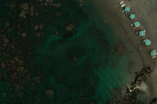 Aerial top nature view above green turquoise Adriatic sea in Albania. Beautiful young woman swimming alone in middle ocean water. girl in swimsuit bikini lying. wide panoramic view marine. summer