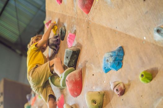 little boy climbing a rock wall in special boots. indoor.