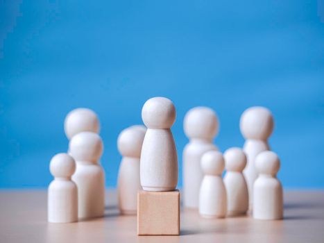 Wooden figure standing on the wooden block to talking leadingship for influence, empowerment and inspiration for crowd. Leader with influence, leader team and successful competition winner concept.