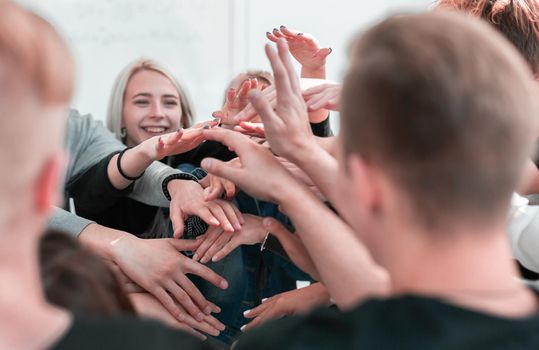 close up. a group of young people joining their palms in a pile . the concept of unity