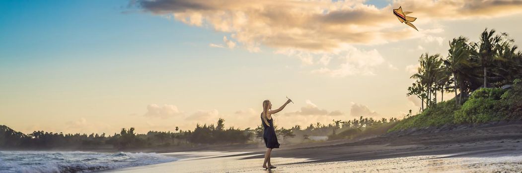 A young woman launches a kite on the beach. Dream, aspirations, future plans. BANNER, LONG FORMAT