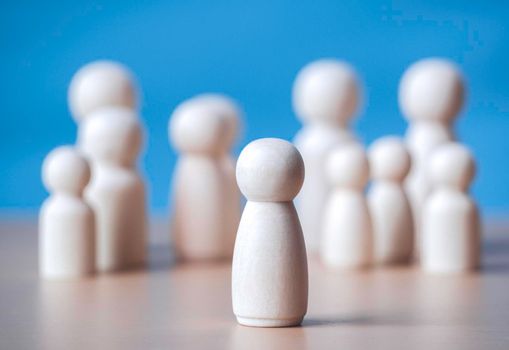 Wooden figure standing on the wooden block to talking leadingship for influence, empowerment and inspiration for crowd. Leader with influence, leader team and successful competition winner concept.