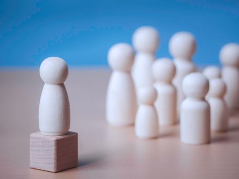 Wooden figure standing on the wooden block to talking leadingship for influence, empowerment and inspiration for crowd. Leader with influence, leader team and successful competition winner concept.