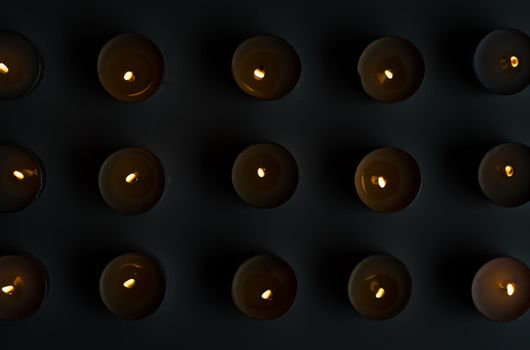 High angle view of lit tea lights arranged on table (selective focus)