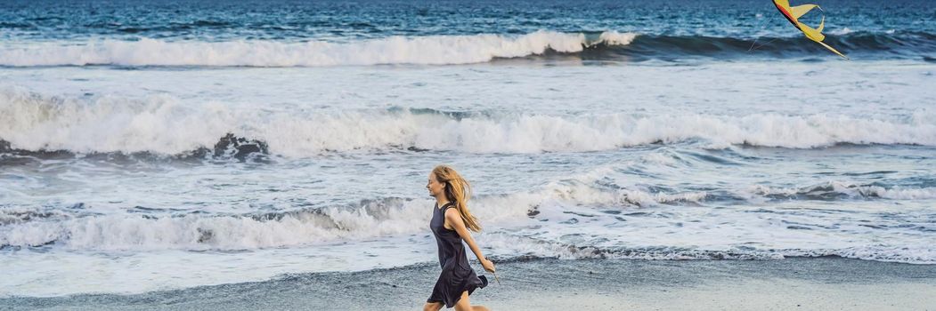 A young woman launches a kite on the beach. Dream, aspirations, future plans. BANNER, LONG FORMAT