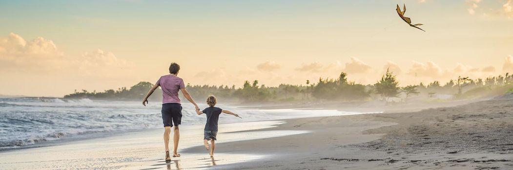 Young father and his son running with kite on the beach. BANNER, LONG FORMAT