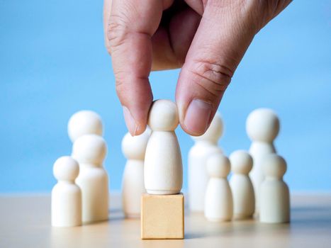 Hand of businessman holding wooden figure standing on wooden block to talking influence, empowerment and inspiration for crowd. Leader with influence, leadership and successful winner concept.