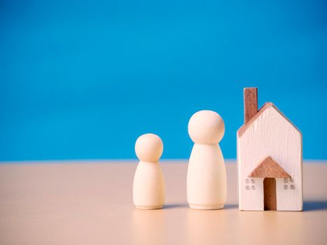 Family wooden figures people standing nearby of tiny wooden house. Concept for family, loan, property ladder, financial, mortgage, real estate investment, taxes and bonus.
