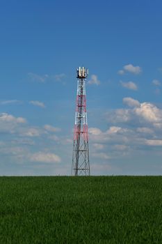 Transmitter for gsm signal of mobile phones in the field. In the background blue sky with clouds. Concept for modern technology and industry - Telecommunication Tower.