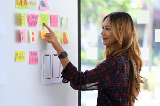 Young woman creative designer is planning application template layout framework for mobile phone on whiteboard.