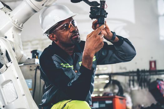 African American factory worker working with adept robotic arm in a workshop . Industry robot programming software for automated manufacturing technology .