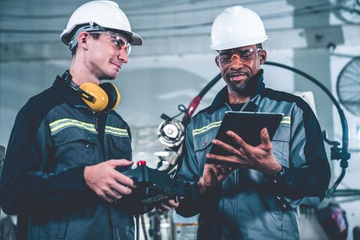 Group of factory job workers using adept machine equipment in a workshop . Industry manufacturing and engineering technology concept .