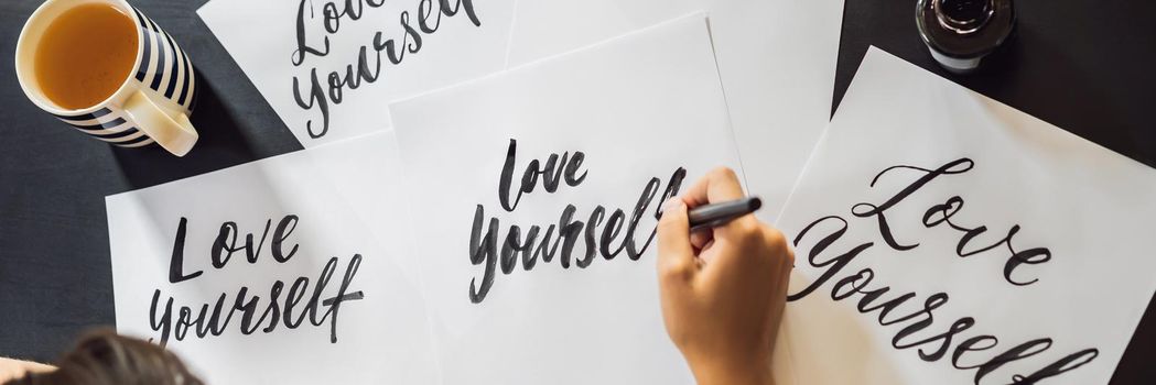 BANNER, LONG FORMAT Love yourself. Calligrapher Young Woman writes phrase on white paper. Inscribing ornamental decorated letters. Calligraphy, graphic design, lettering, handwriting, creation concept.