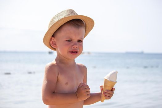 the child cries and eats ice cream on the beach. selective focus