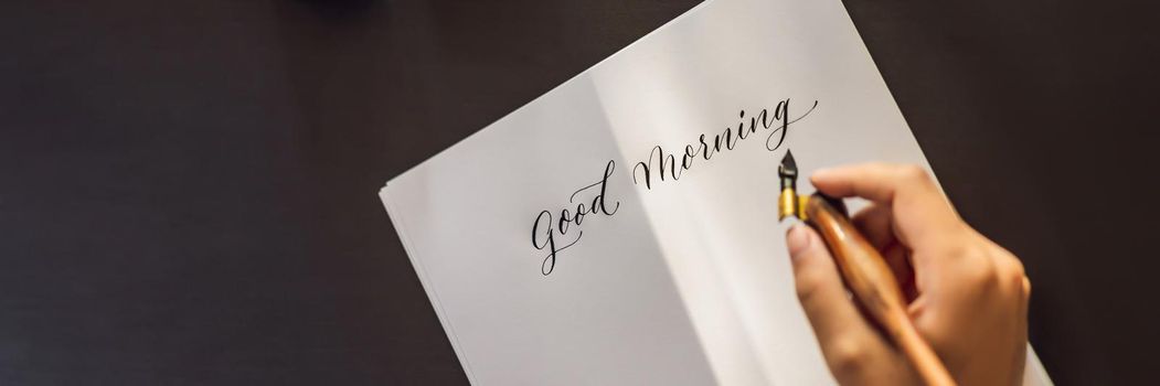 BANNER, LONG FORMAT Good morning. Calligrapher Young Woman writes phrase on white paper. Inscribing ornamental decorated letters. Calligraphy, graphic design, lettering, handwriting, creation concept.