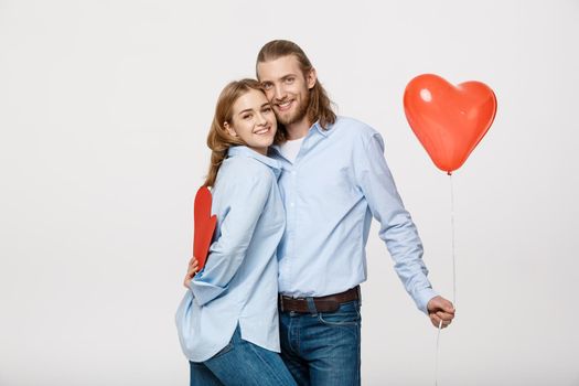 Portrait of young man and woman holding a heart- shaped balloon and paper.