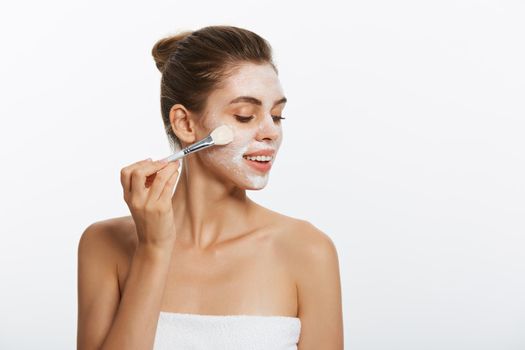 Portrait beautiful naked woman apply cosmetic white clay mask on with brush. Isolated on a white background. concept of beauty and health.