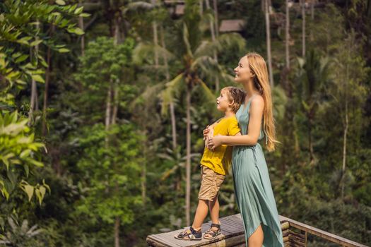 Mom and son on the rice field in the background of rice terraces, Ubud, Bali, Indonesia. Traveling with children concept. Teaching children in practice.