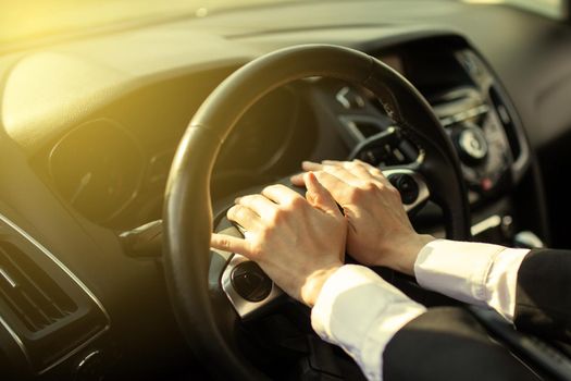 The girl clicks a hand on the signal on the steering wheel of the car