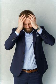 a handsome brutal bearded and long-haired man is holding his hands by the head, worrying, a stylish businessman on a white background. High quality photo